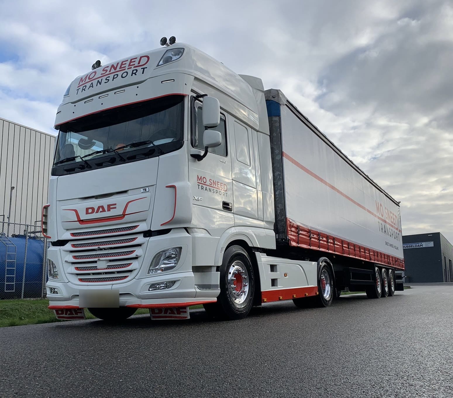 Trekker met schuifzeiloplegger met een rode streep, voor een loods